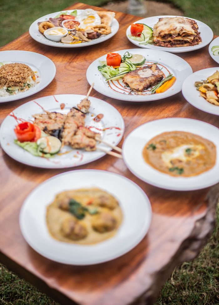 A variety of delicious dishes plated elegantly on a rustic wooden table outdoors.