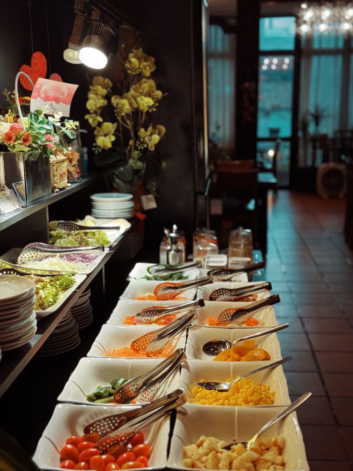 A beautifully arranged indoor buffet featuring fresh salads and various toppings in an elegant setting.